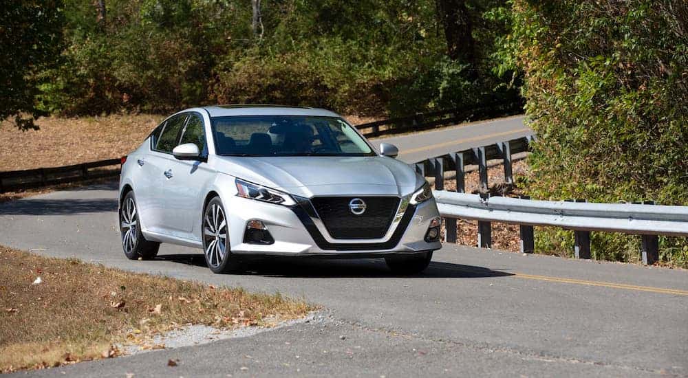 A silver used 2021 Nissan Altima driving on a curved road