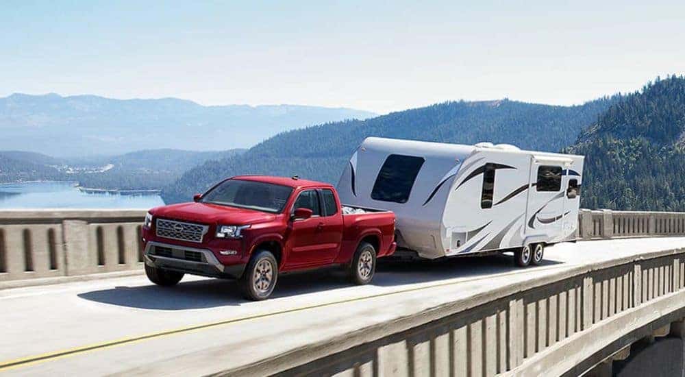 Red 2024 Nissan Frontier towing a camper 