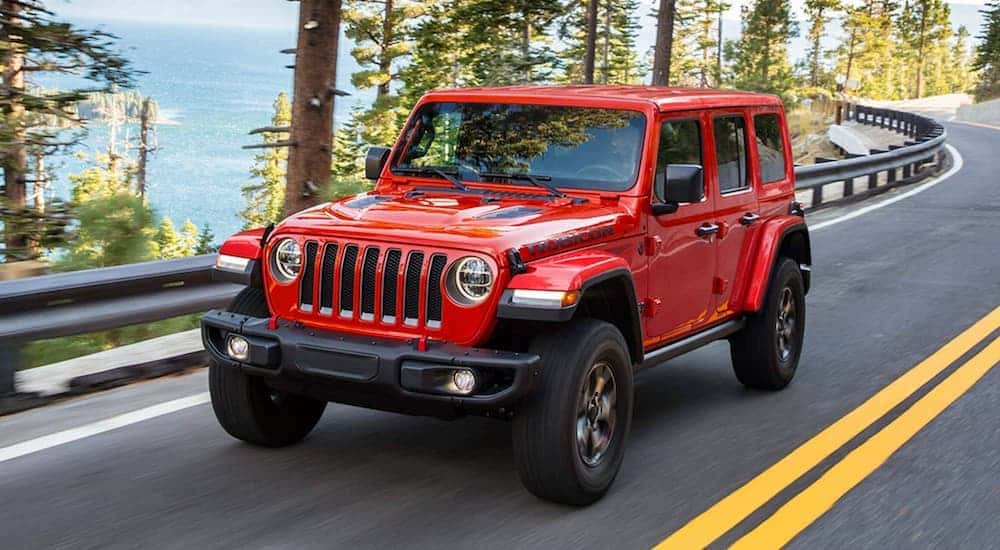 A red 2021 Jeep Wrangler driving to view a used Jeep Wrangler for sale in Knoxville.