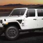 A white 2023 Jeep Wrangler Freedom Edition parked offroad.