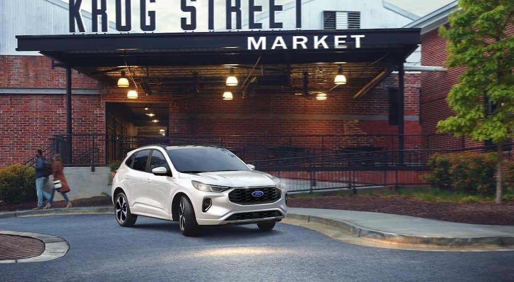 A white 2023 Ford Escape ST-Line parked outside a market