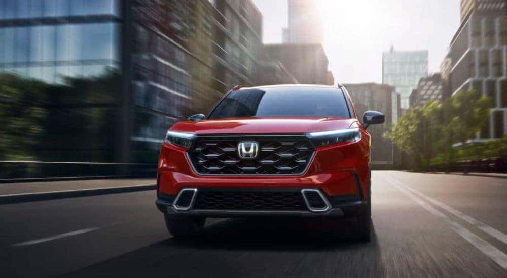A red 2024 Honda CR-V driving in a city