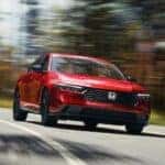 A red 2023 Honda Accord driving down a road