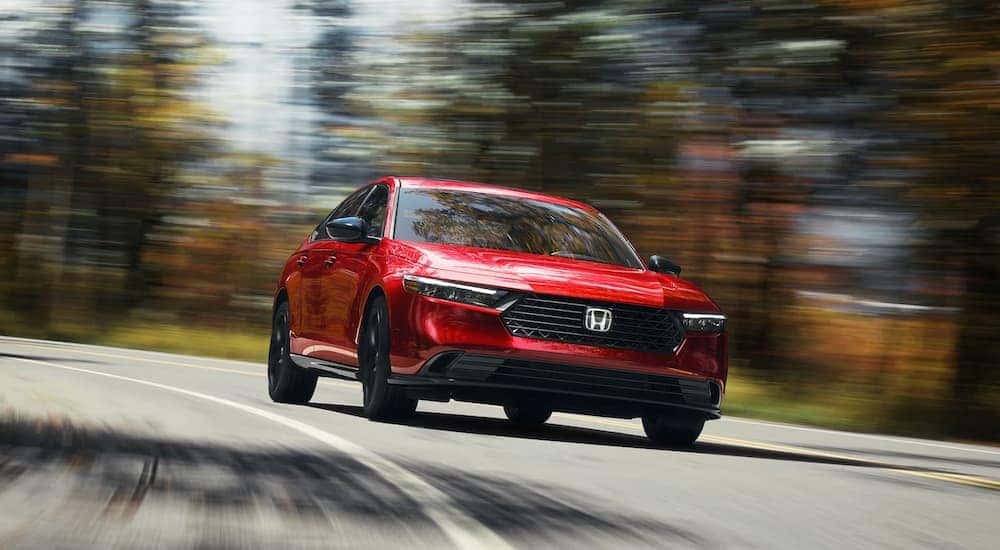 A red 2023 Honda Accord driving down a road