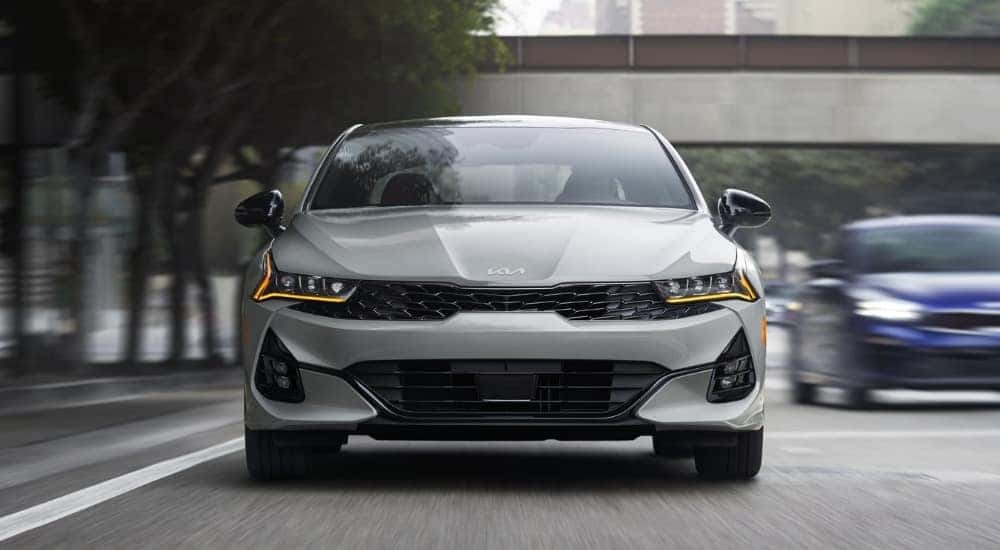 A gray 2024 Kia K5 driving in a city