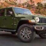 A green 2024 Jeep Wrangler Sahara Unlimited parked off-road