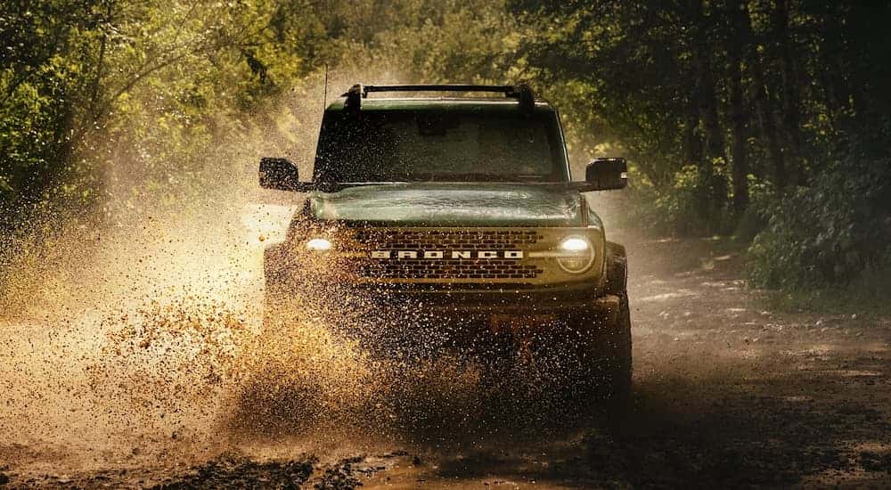 A black 2025 Ford Bronco off-roading in mud