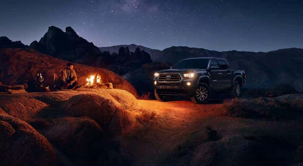 Black 2023 Toyota Tacoma parked at a campsite at night
