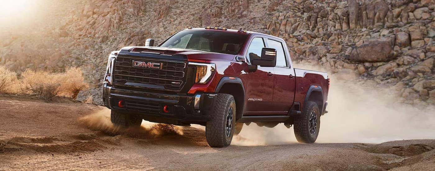 A red 2025 GMC Sierra 2500 HD AT4 off-roading on sand