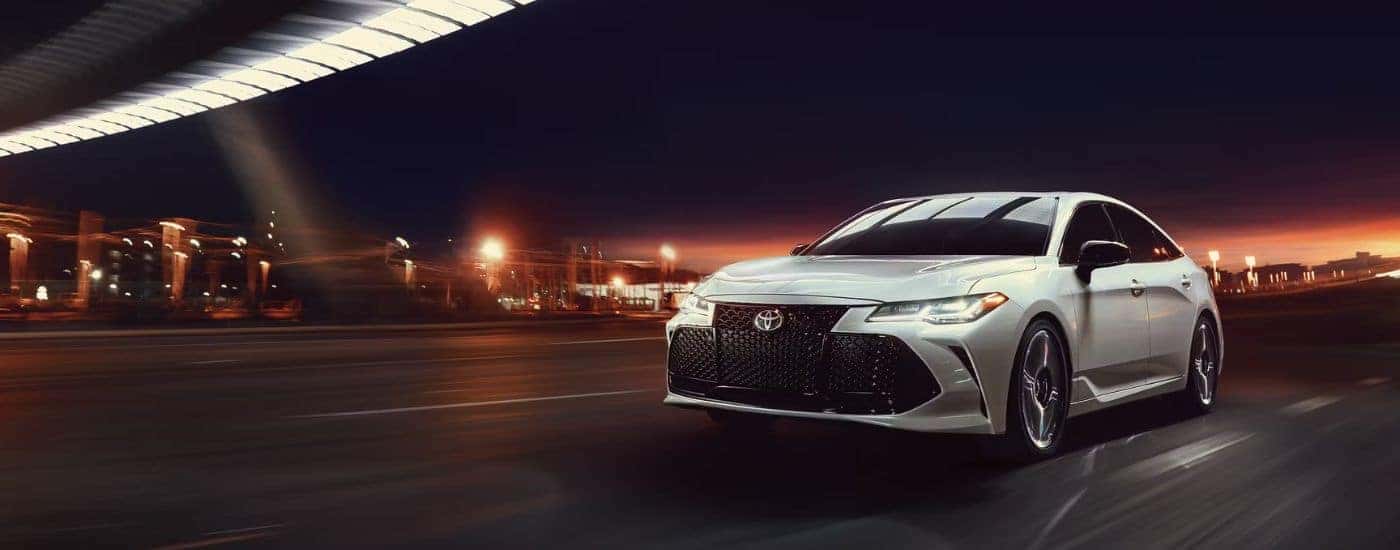 A white 2020 Toyota Avalon driving through a city at night.