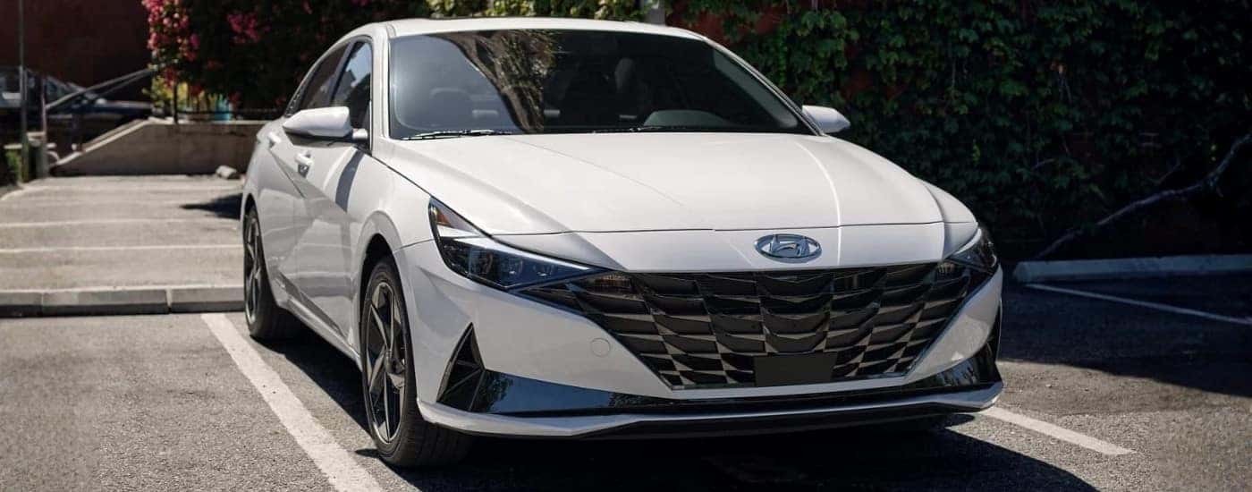 A white 2021 Hyundai Elantra Hybrid Limited parked at a used car dealer.
