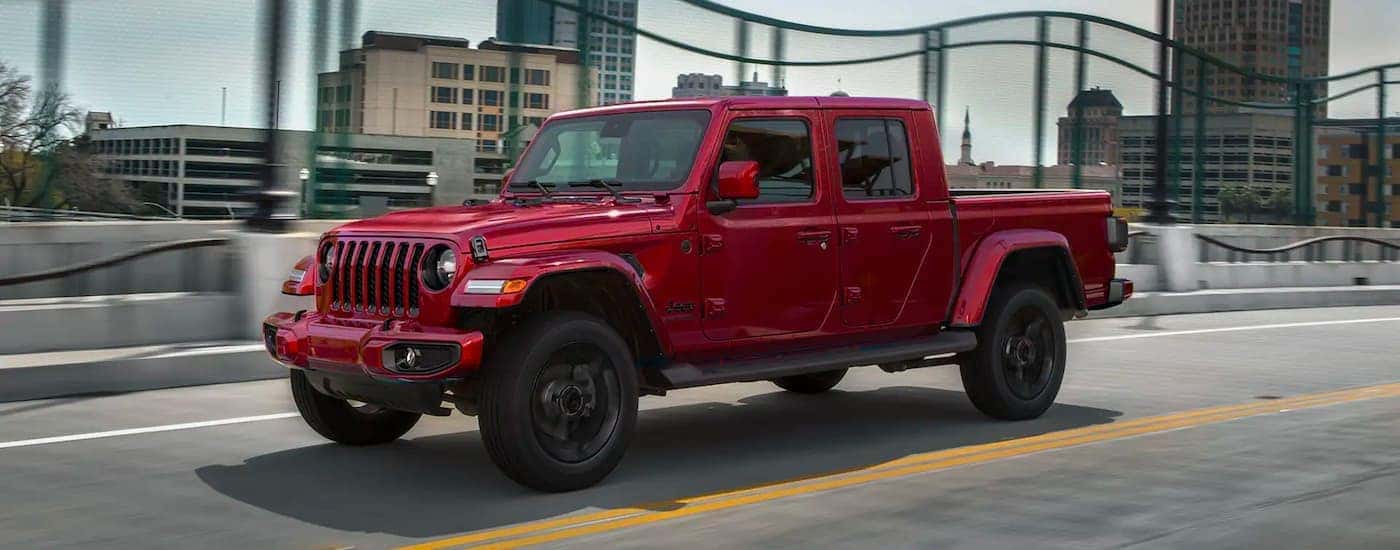 Red 2021 Jeep Gladiator driving across a bridge.