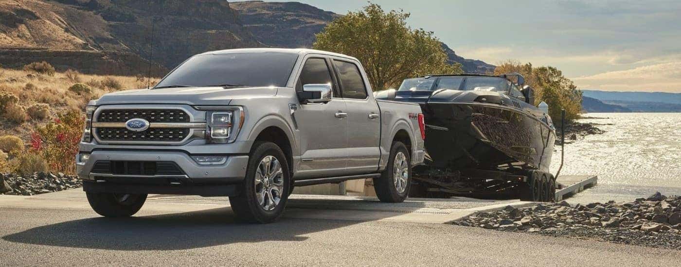 Silver 2023 Ford F1-50 towing a boat.