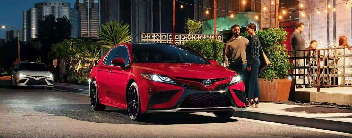 Red 2023 Toyota Camry parked by a city curb with a front angle view