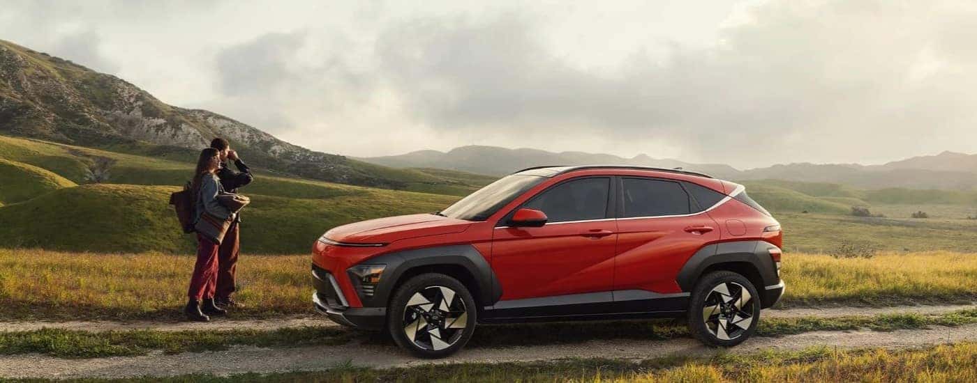 Red 2024 Hyundai Kona parked on a trail with a couple