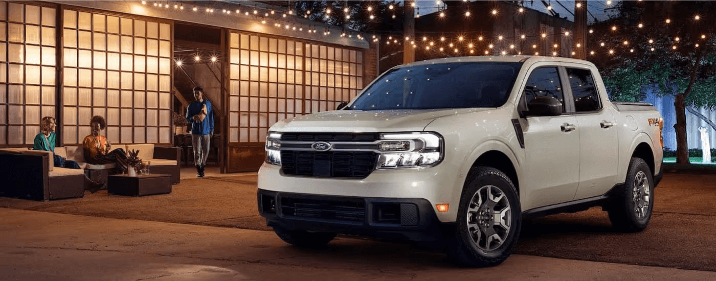 A white 2024 Ford Maverick LARIAT parked under lights at night.