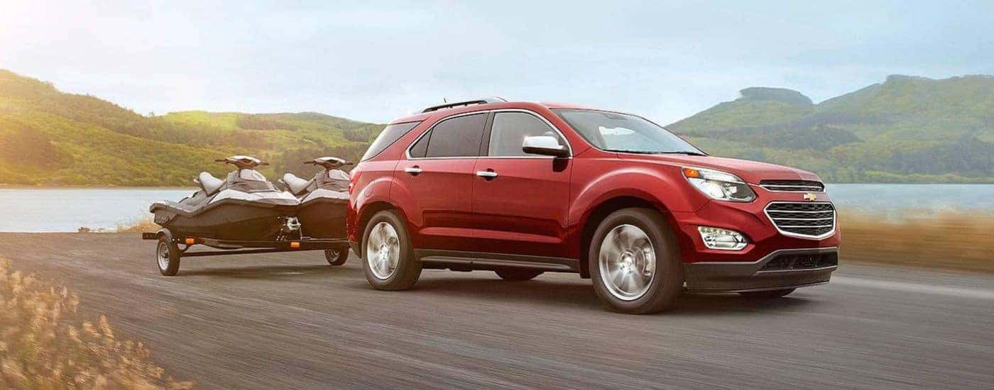 Red 2-16 Chevy Equinox towing a boat away from a lake