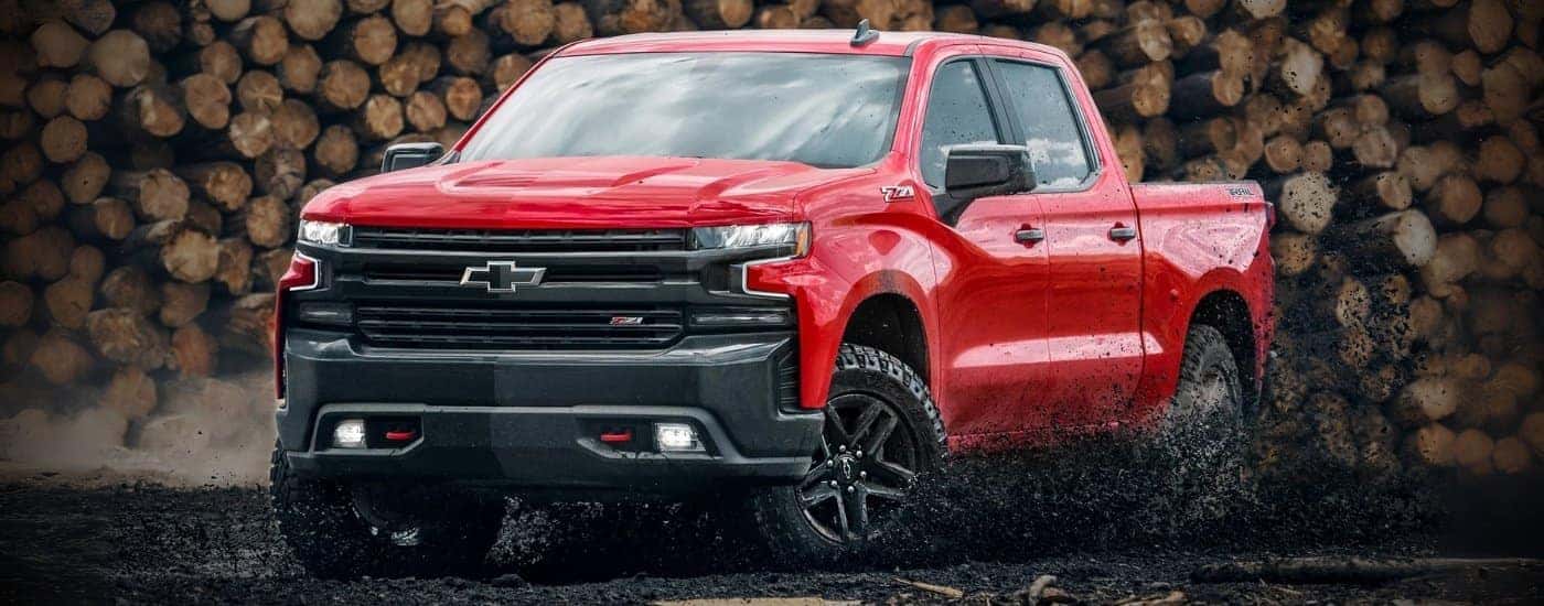 Red 2022 Chevy Silverado 1500 TrailBoss with logs behind it.