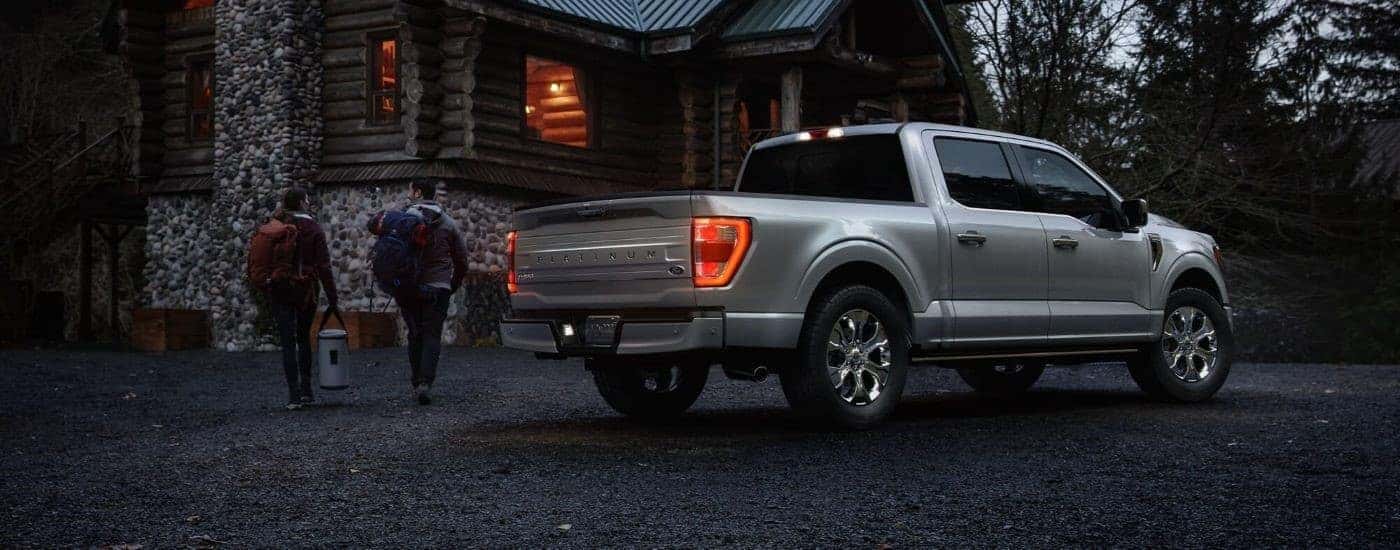 A silver 2023 Ford F-150 Platinum is shown parked near a cabin.