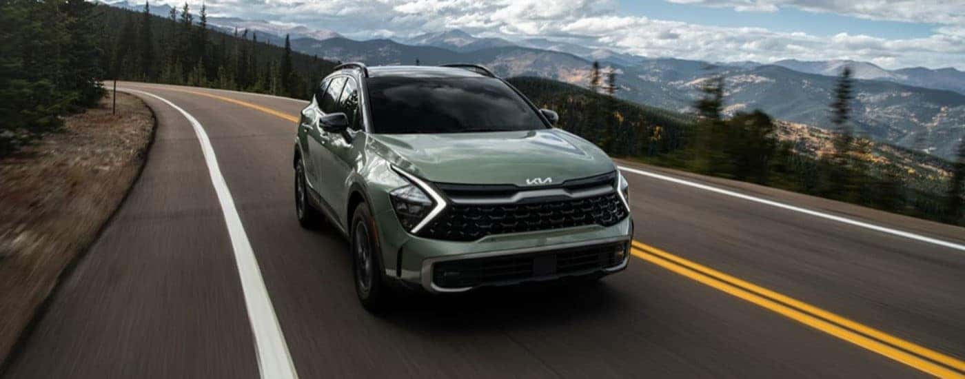 2023 Kia Sportage driving by mountains.