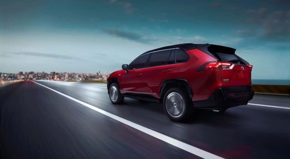 Red 2023 Toyota RAV4 driving on the road at twilight.