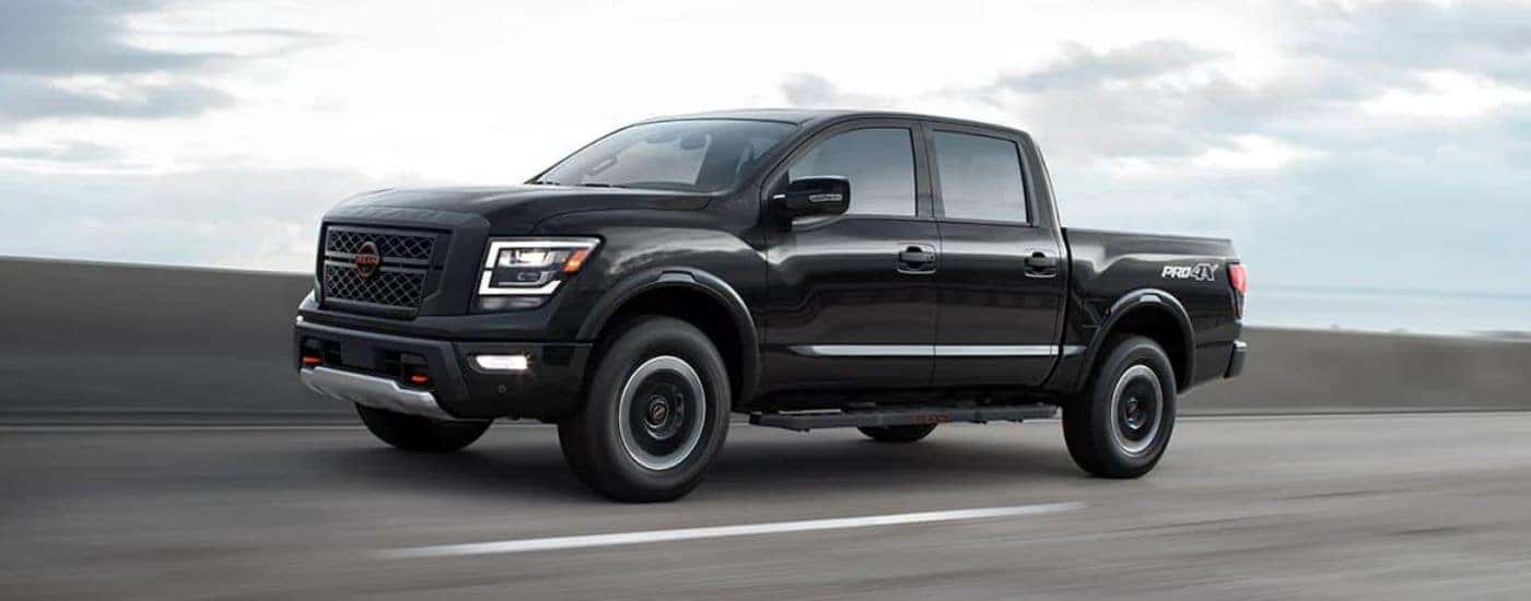 Black 2024 Nissan Titan Pro 4X driving on a road.