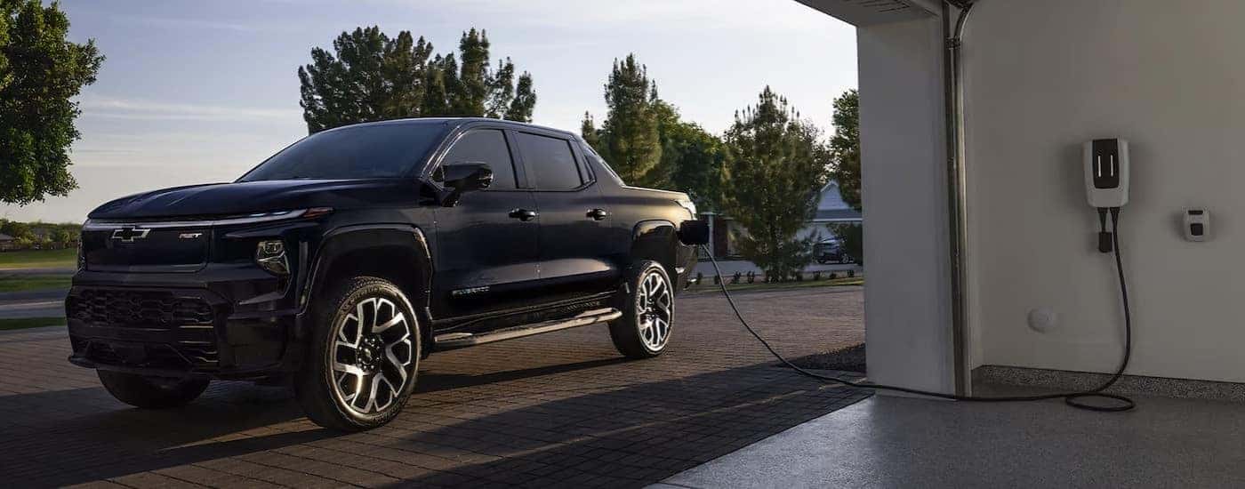 Black 2023 Chevy Silverado EV plugged into a home charger.