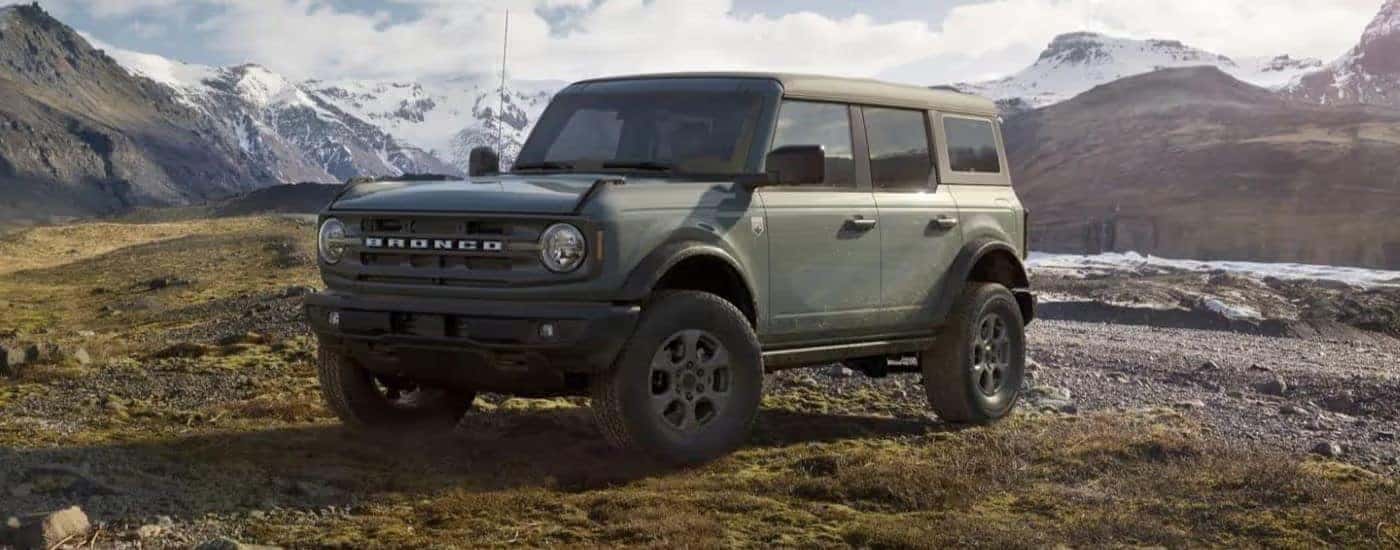 Sage green 2023 Ford Bronco parked off-road in the mountains.