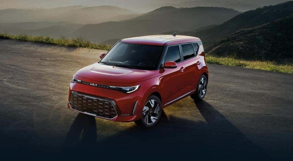 Red 2024 Kia Soul parked in the dirt with mountains behind it.