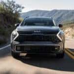 A gray 2024 Kia Sportage shown driving a paved mountain road head-on.