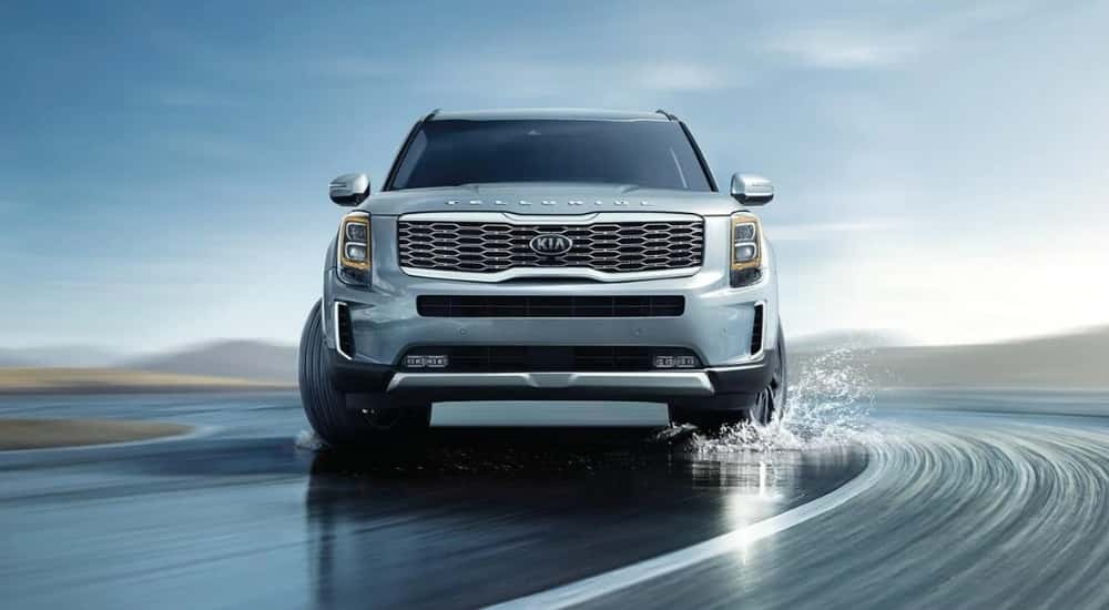 A light blue 2020 Kia Telluride driving on a wet shoreline.