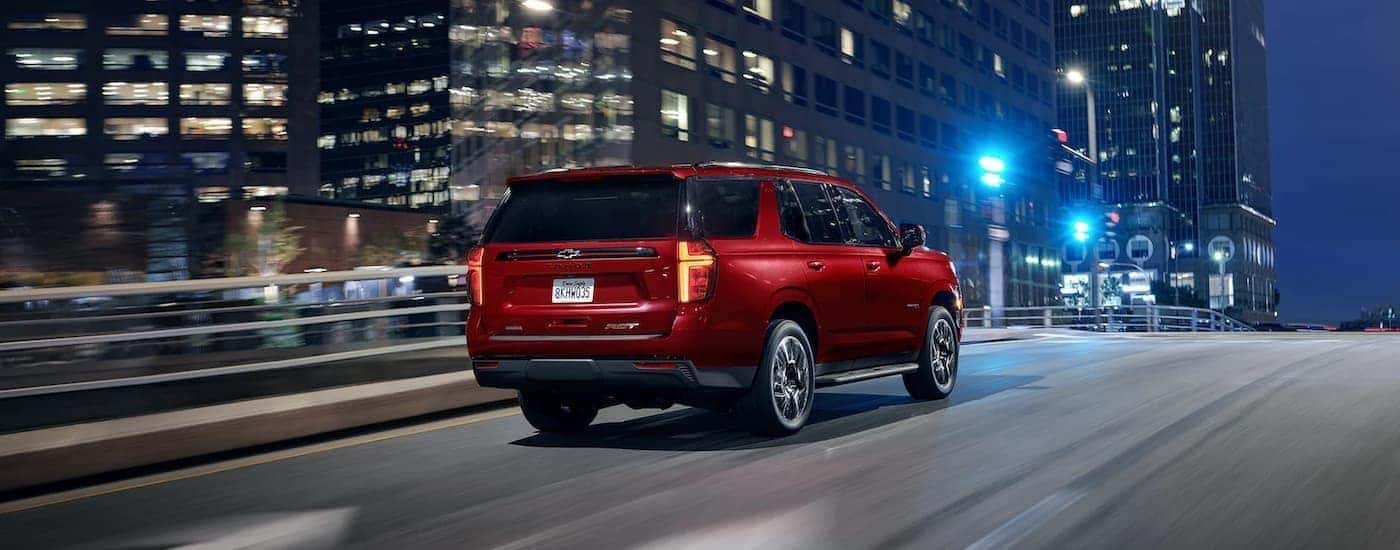 Red 2022 Chevy Tahoe driving through a city at night