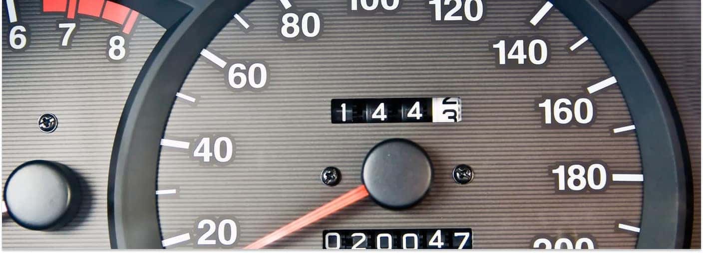 Close-up of an automotive dashboard instrument cluster showing an analog speedometer and odometer.
