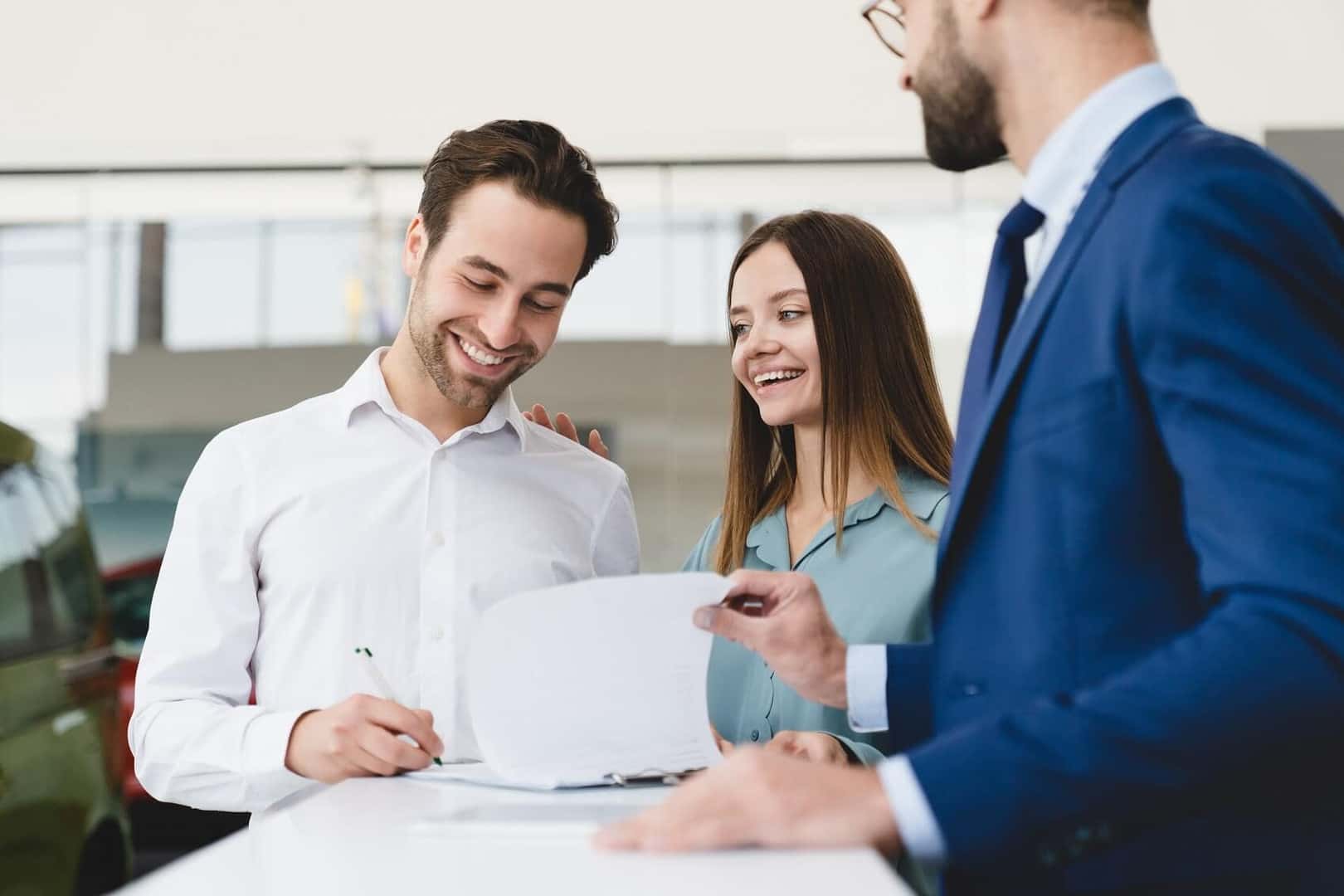 Financing sales man with couple, showing paperwork