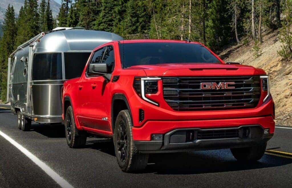 Red Sierra 1500 towing a camper on the road