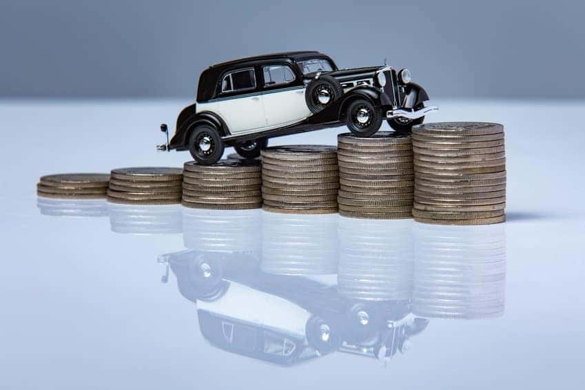 Toy car driving up a stack of coins symbolizing the Nissan finance process
