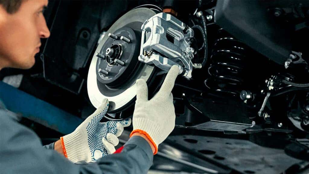 A technician inspecting a vehicles brake system.