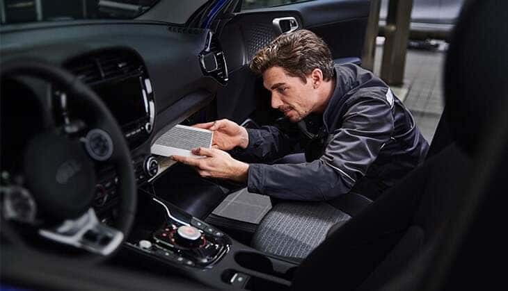 A Kia technician installing a new cabin air filter.