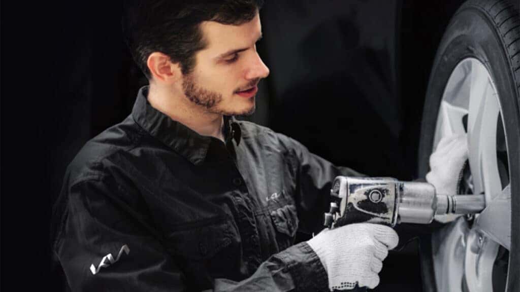 A Kia technician performing a tire rotation.
